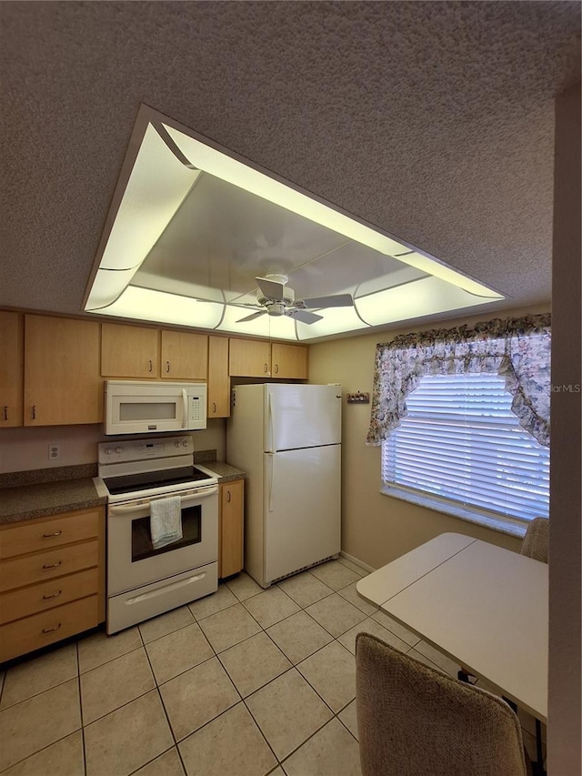 kitchen with light brown cabinets, a tray ceiling, light tile patterned flooring, white appliances, and a ceiling fan