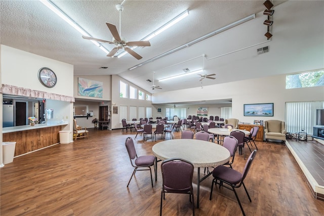 dining room with a ceiling fan, wood finished floors, visible vents, high vaulted ceiling, and a textured ceiling