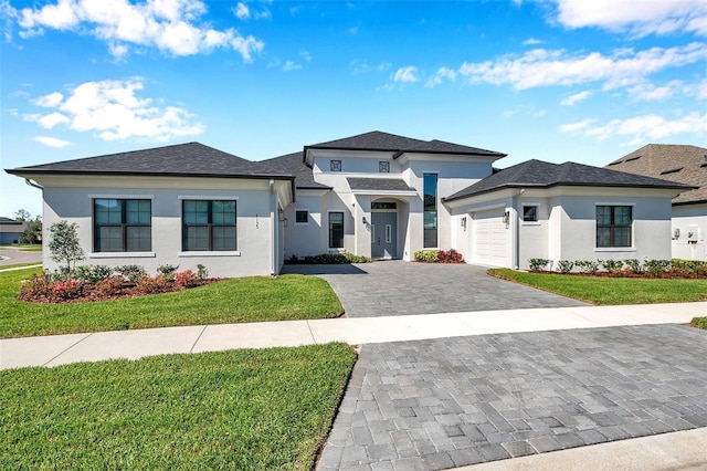 prairie-style house featuring a garage, stucco siding, decorative driveway, and a front yard