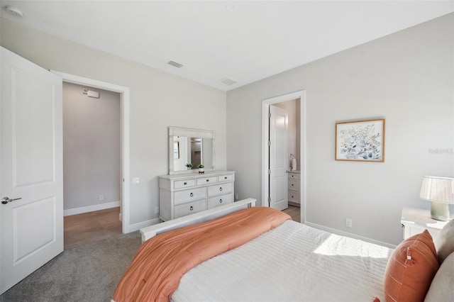 bedroom featuring baseboards, light carpet, visible vents, and ensuite bathroom