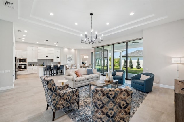 living room featuring a tray ceiling, baseboards, an inviting chandelier, and visible vents