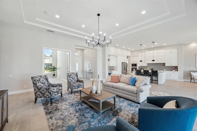 living area with a raised ceiling, a notable chandelier, recessed lighting, and baseboards