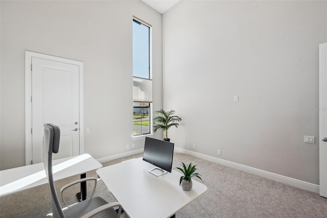 office featuring carpet flooring, baseboards, and a towering ceiling