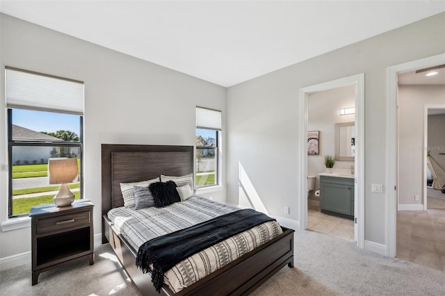 bedroom featuring light carpet, visible vents, connected bathroom, and baseboards