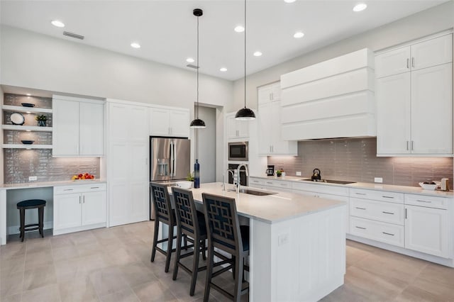 kitchen with visible vents, built in microwave, a breakfast bar area, black electric cooktop, and a sink