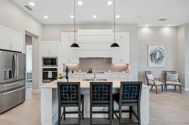 kitchen with visible vents, a sink, decorative backsplash, stainless steel appliances, and a kitchen bar