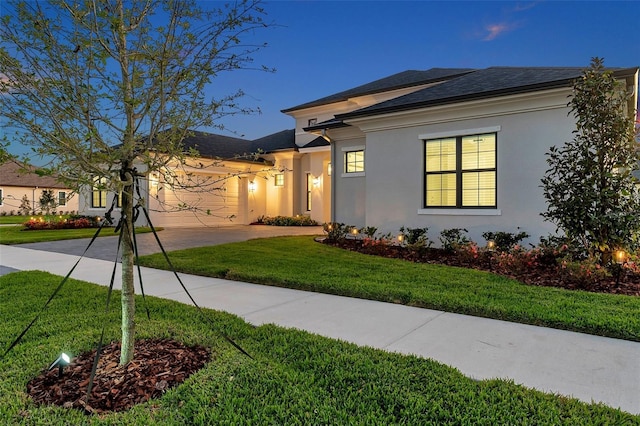 ranch-style home featuring stucco siding, roof with shingles, concrete driveway, a front yard, and a garage