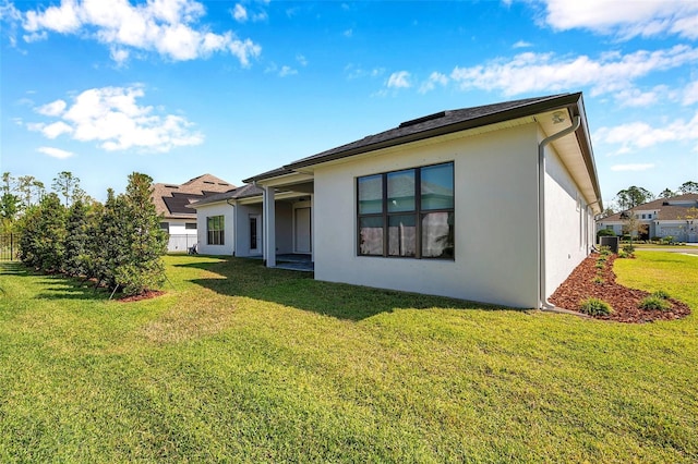 back of property featuring a lawn and stucco siding