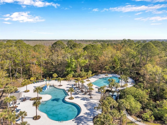 community pool with a patio area and a view of trees