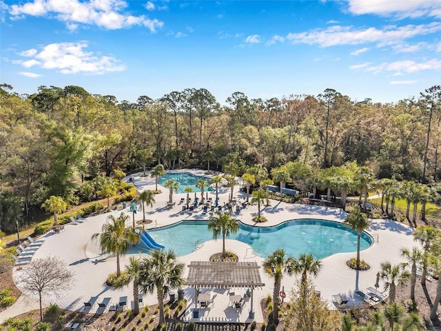 pool featuring a wooded view and a patio