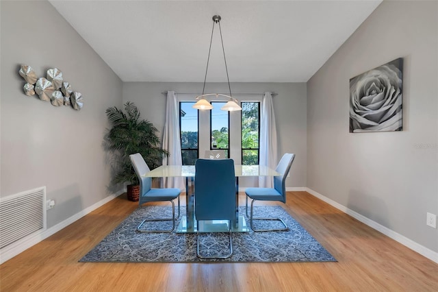 dining room featuring vaulted ceiling, wood finished floors, visible vents, and baseboards