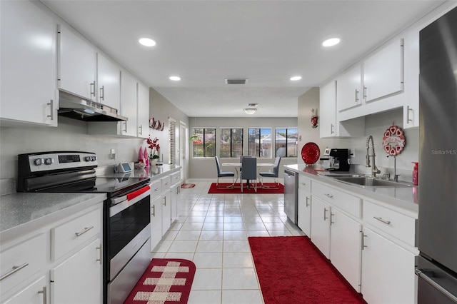 kitchen featuring visible vents, under cabinet range hood, light tile patterned floors, stainless steel appliances, and a sink