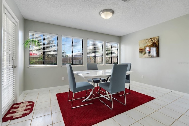 dining room featuring tile patterned floors, a textured ceiling, and baseboards