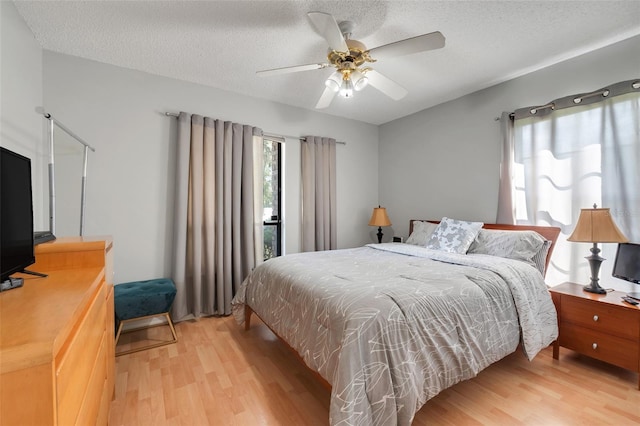 bedroom with access to exterior, a ceiling fan, light wood-type flooring, and a textured ceiling