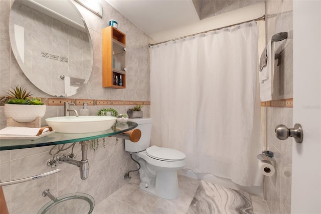 full bath featuring a sink, tile patterned floors, toilet, tile walls, and shower / tub combo with curtain