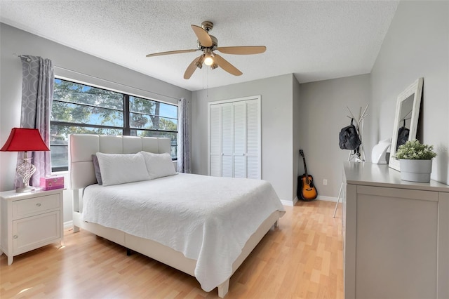 bedroom with a closet, baseboards, light wood-style floors, and a textured ceiling