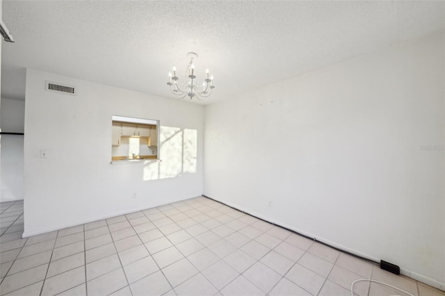 unfurnished room featuring light tile patterned floors, visible vents, a textured ceiling, and an inviting chandelier