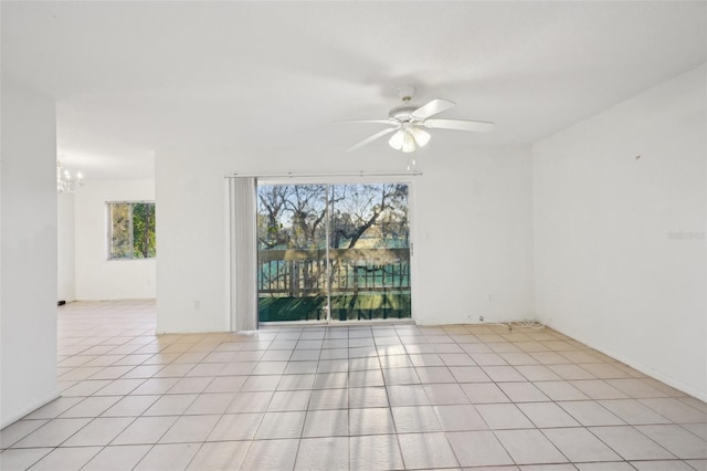 spare room with plenty of natural light, light tile patterned flooring, and ceiling fan with notable chandelier