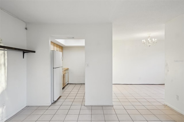 kitchen featuring a chandelier, freestanding refrigerator, and light tile patterned flooring