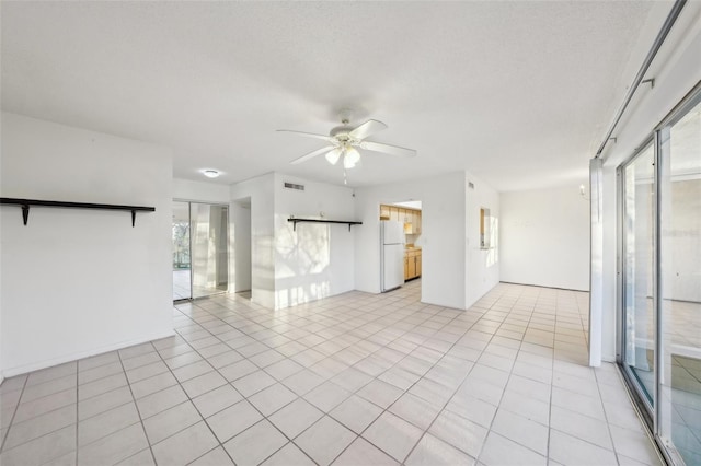 empty room featuring a textured ceiling, light tile patterned floors, visible vents, and ceiling fan