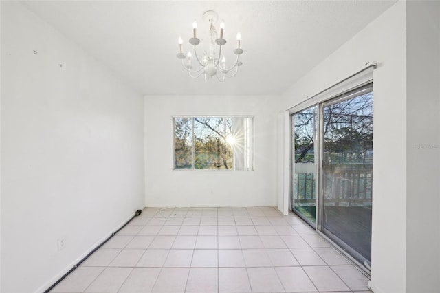 empty room featuring an inviting chandelier, light tile patterned floors, baseboards, and a wealth of natural light