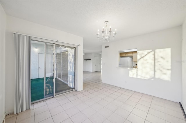 spare room with a chandelier, visible vents, a textured ceiling, and light tile patterned flooring