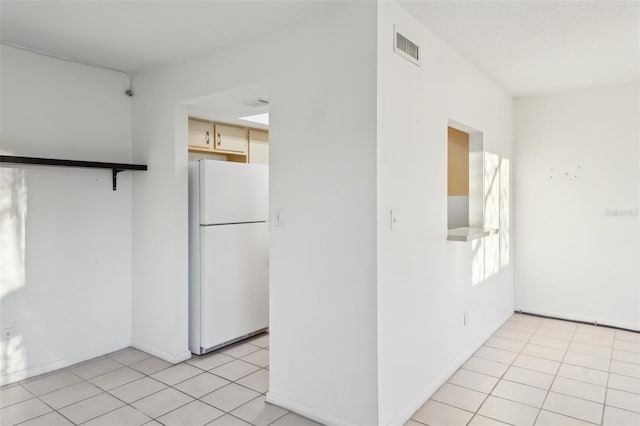 kitchen with light tile patterned floors, baseboards, visible vents, and freestanding refrigerator