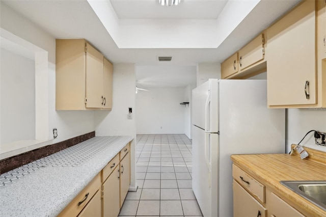 kitchen with visible vents, light tile patterned flooring, freestanding refrigerator, light countertops, and cream cabinets