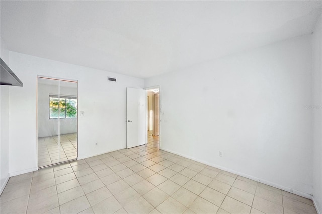 spare room with light tile patterned floors, visible vents, and baseboards