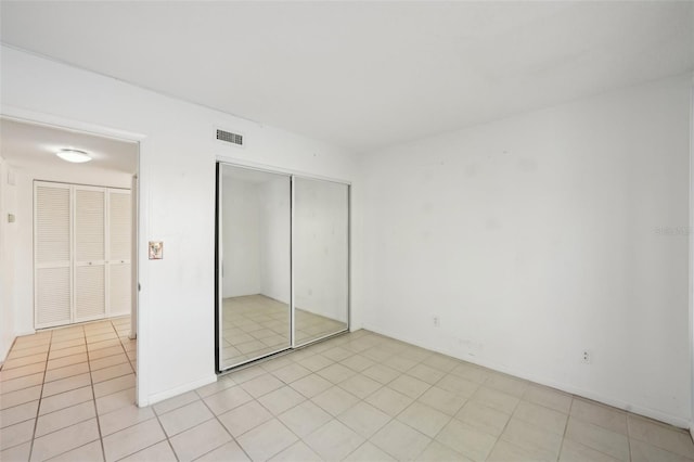 unfurnished bedroom with light tile patterned flooring, visible vents, and a closet