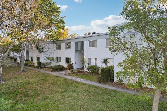 view of front of house with stucco siding and a front lawn