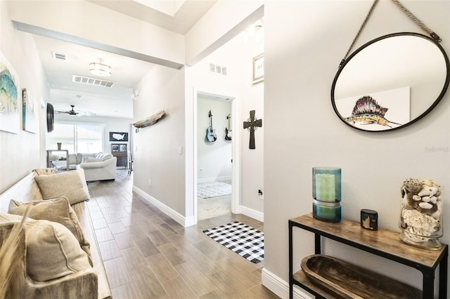 hallway featuring wood finished floors, visible vents, and baseboards