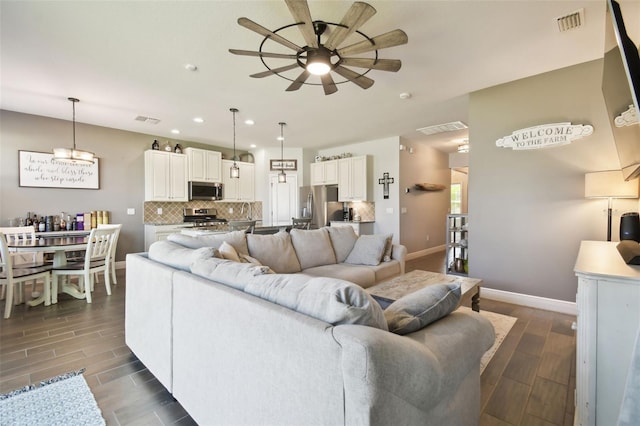 living room featuring wood tiled floor, visible vents, and ceiling fan