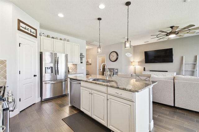 kitchen with a sink, appliances with stainless steel finishes, decorative backsplash, ceiling fan, and wood tiled floor