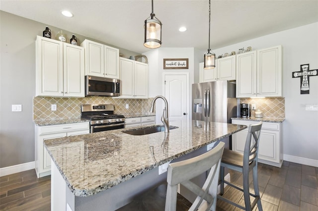 kitchen featuring light stone countertops, baseboards, a breakfast bar, a sink, and appliances with stainless steel finishes