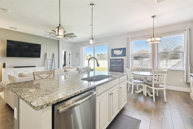 kitchen with open floor plan, an island with sink, stainless steel dishwasher, a ceiling fan, and a sink