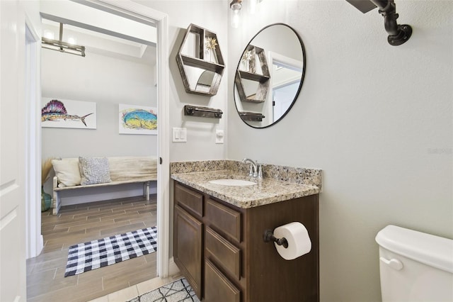 bathroom with toilet, vanity, and wood finish floors