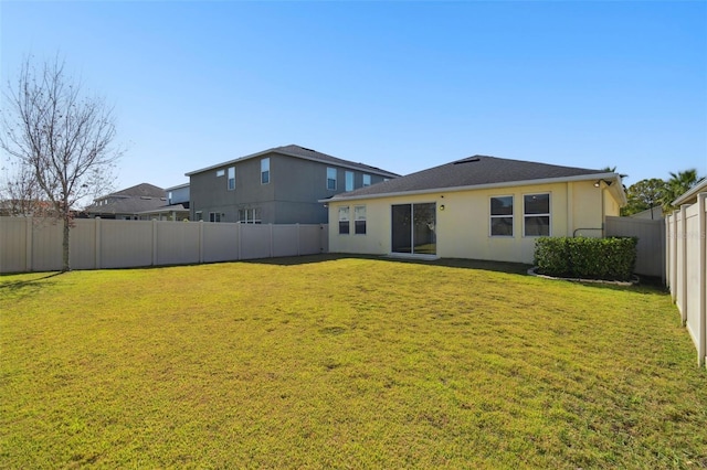 back of house featuring stucco siding, a lawn, and a fenced backyard