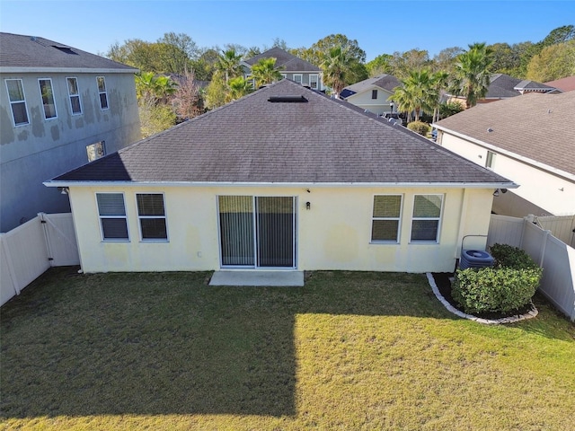 back of property with a fenced backyard, stucco siding, a shingled roof, and a yard