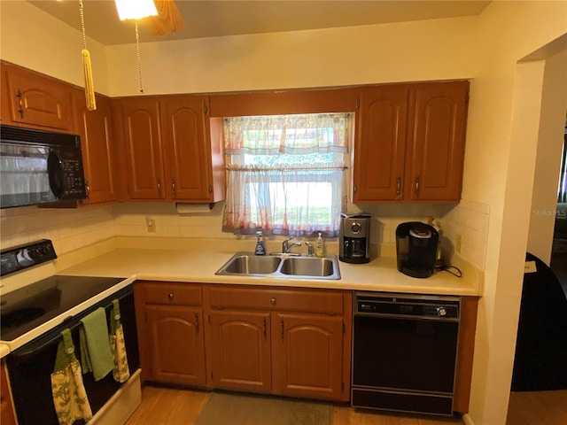 kitchen with black appliances, light countertops, backsplash, and a sink