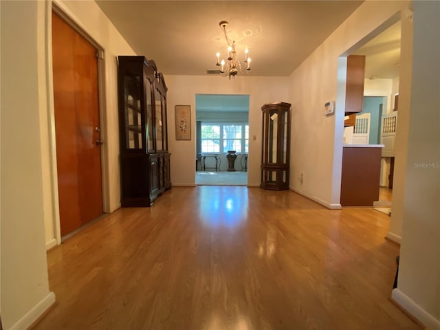 unfurnished dining area featuring baseboards, wood finished floors, visible vents, and a chandelier