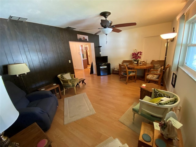 living area with ceiling fan, visible vents, and wood finished floors