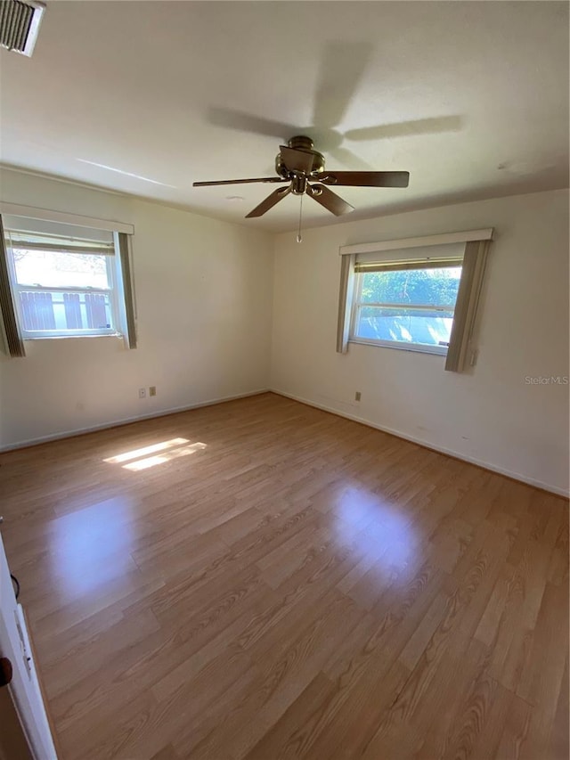 spare room with a wealth of natural light, visible vents, and wood finished floors