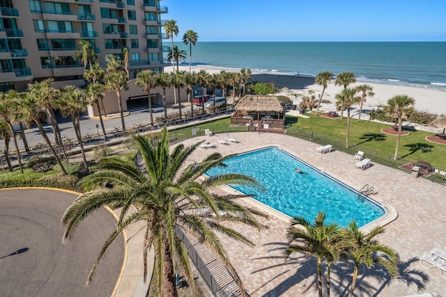 community pool with a water view, a patio, fence, a gazebo, and a view of the beach