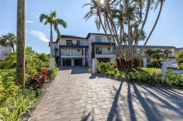 view of front facade featuring a balcony, stucco siding, decorative driveway, and a garage