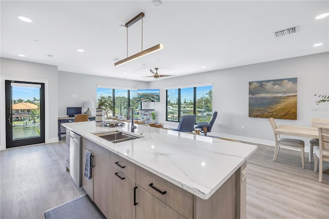 kitchen with visible vents, light wood-style flooring, a sink, light stone counters, and stainless steel dishwasher