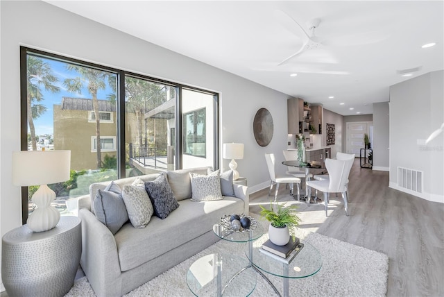 living room featuring wood finished floors, visible vents, baseboards, recessed lighting, and ceiling fan