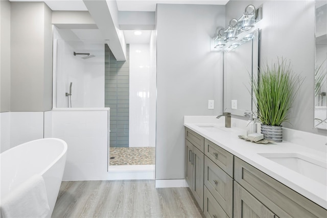 full bathroom with double vanity, a soaking tub, walk in shower, and a sink