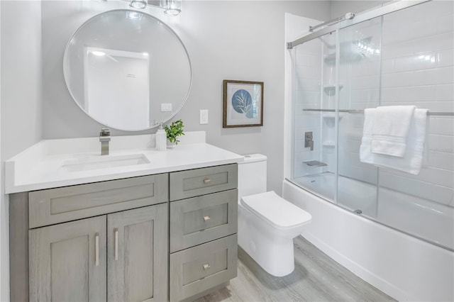 full bathroom featuring vanity, toilet, wood finished floors, and bath / shower combo with glass door