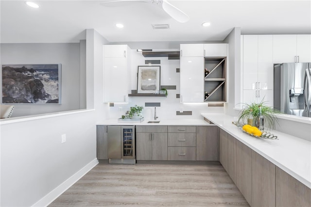 bar featuring beverage cooler, visible vents, stainless steel fridge, and light wood-type flooring